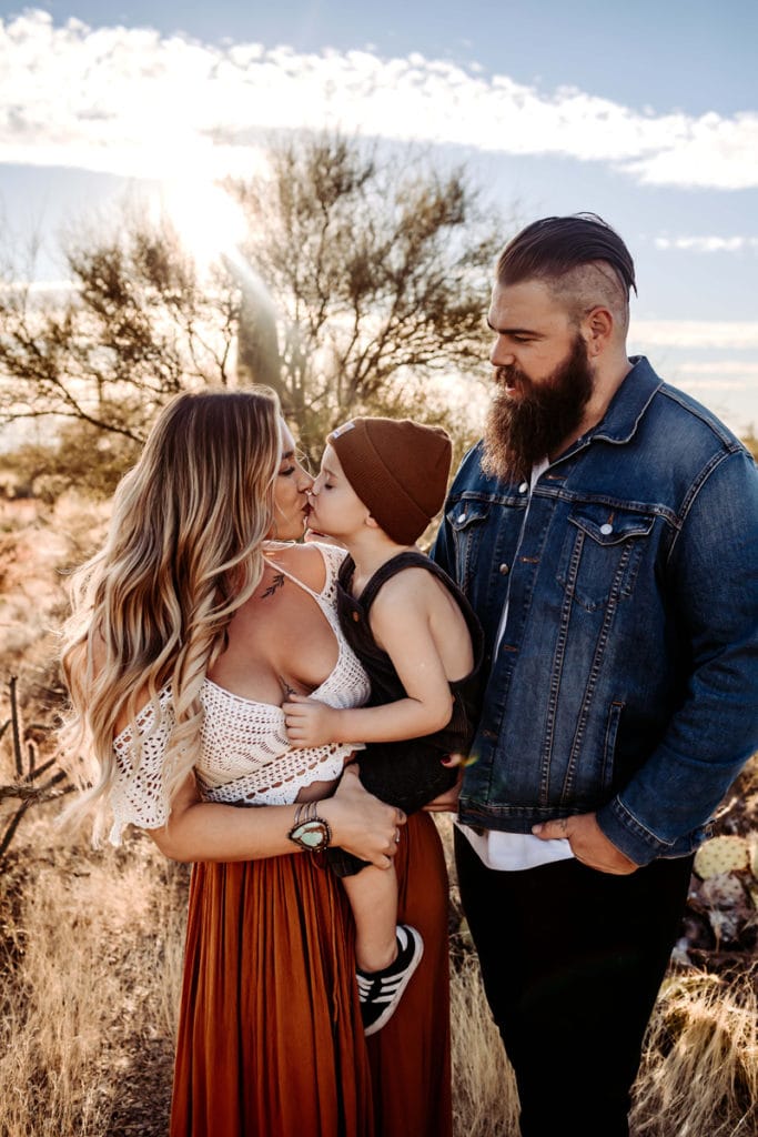 Family Photographer, mom gives son a kiss as dad looks on, they stand in the desert