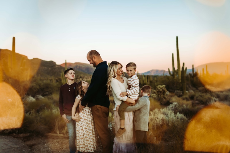 Family of five admire each other in the desert before cacti